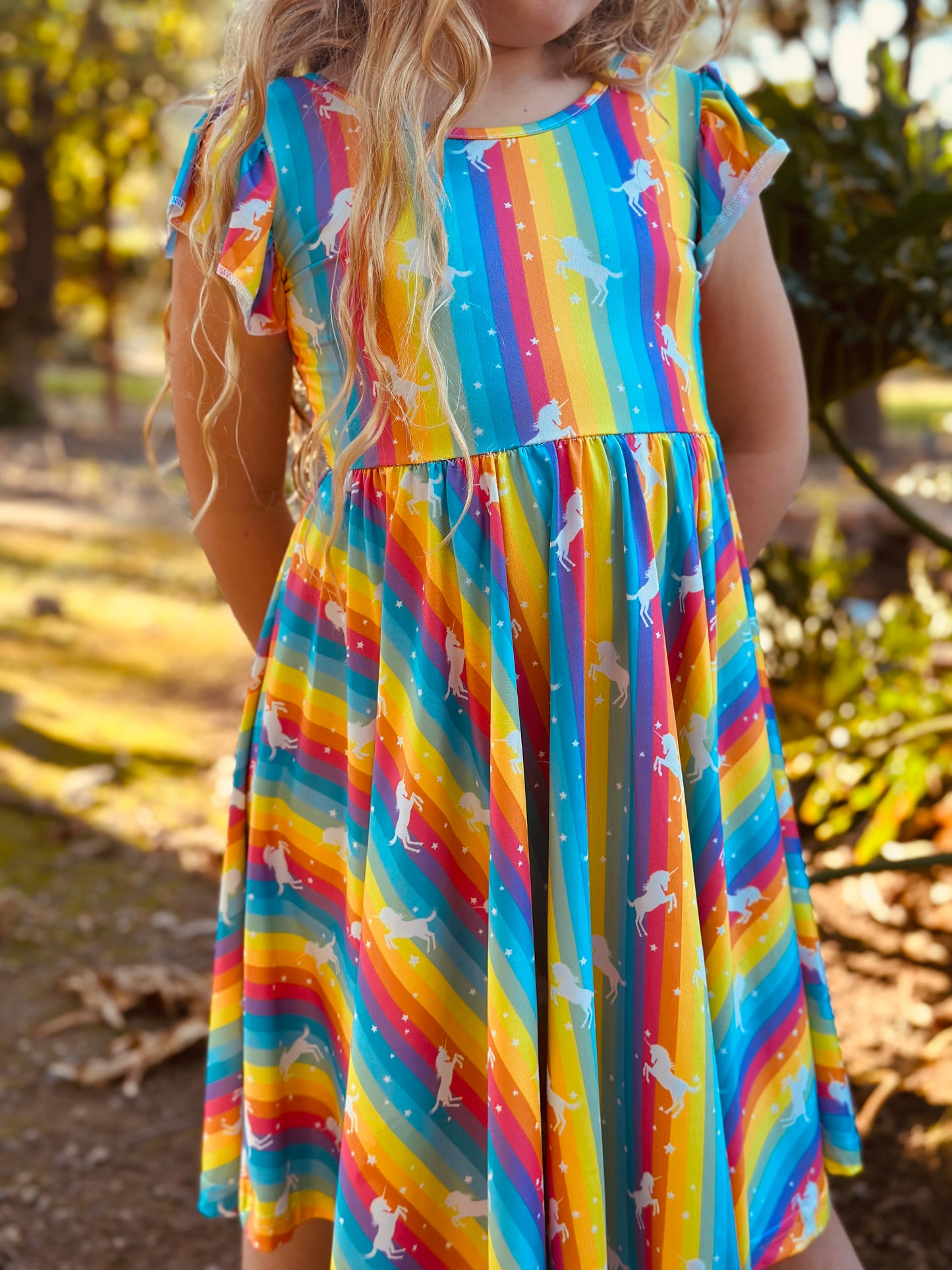 Child wearing rainbow unicorn empire dress with flutter sleeves
